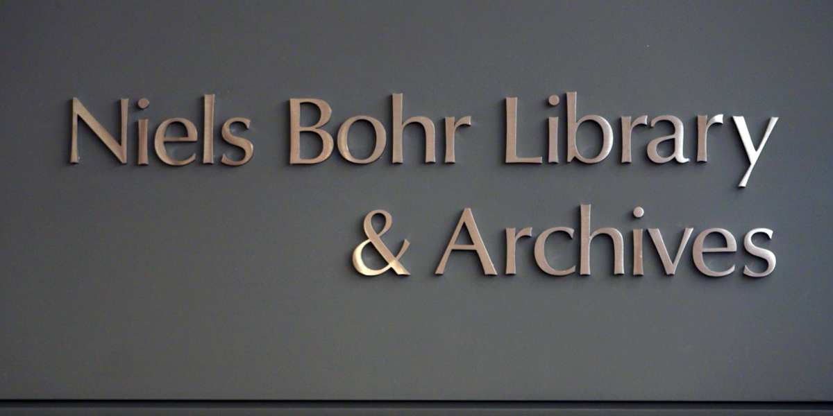 Three-dimensional metallic lettering mounted on a dark gray wall that reads: "Niels Bohr Library & Archives."
